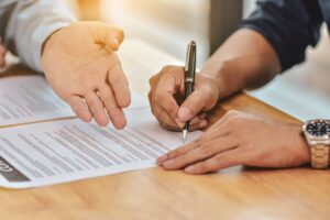 close up hand holding pen sign contract document 1